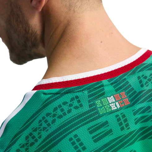 Close-up of the back of a green Mexico soccer jersey featuring a "SOMOS MÉXICO" badge below a red and white collar.