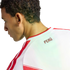 Profile view of a man wearing a white Peru national team jersey with red stripes and the word "PERÚ" on the back collar against a black background.