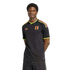 A man wears a black Adidas soccer jersey with neon lime and pink accents and an "FPF" crest. He is posed with hands behind his back against a solid black background.