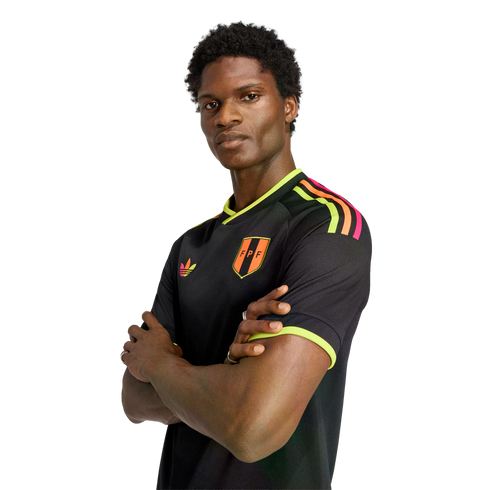 Man with arms crossed wearing a black FPF jersey with neon yellow and orange accents, against a black background.