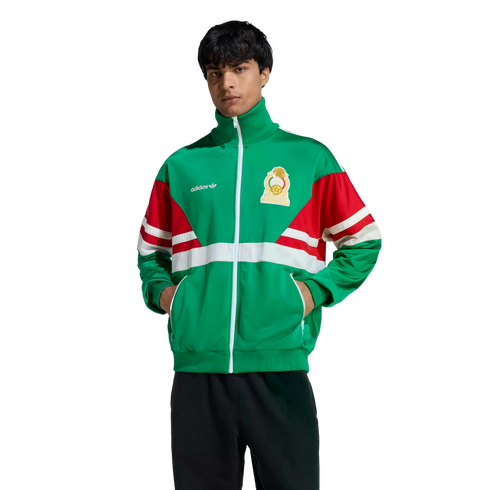 A man in a green, red, and white Adidas track jacket with the Mexico national team crest poses against a black background.