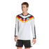 A man modeling a white long-sleeved Germany soccer jersey with a black, red, and yellow chevron design and matching black shorts against a solid black background.