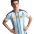 A man wearing the Argentina national football team home jersey with light blue and white stripes and gold accents, including the 2022 FIFA World Champions patch, posing with hands on his hips.
