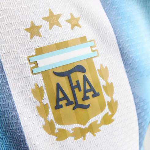 Close-up of the Argentina national football team jersey showing the AFA crest with three gold stars on light blue and white vertical stripes.