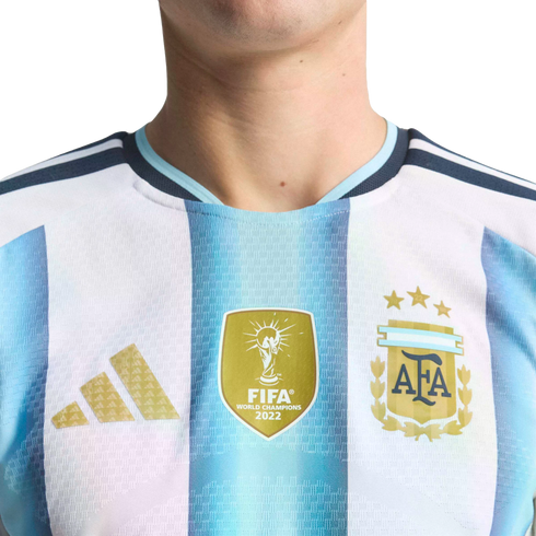 Close-up of an Argentina national football jersey with blue and white stripes, featuring the FIFA World Champions 2022 patch and the AFA crest with three stars.