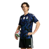 A young man models a black and blue patterned Argentina soccer jersey and shorts while holding a soccer ball against a solid black background.
