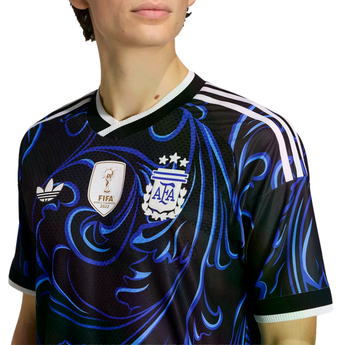 Person wearing a black Argentina soccer jersey with blue swirls, a 2022 FIFA World Champions patch, AFA crest with three stars, and white Adidas shoulder stripes.
