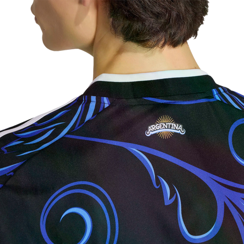 Close-up of the back of a black Argentina soccer jersey featuring vibrant blue and purple swirls and an Argentina sun logo on the neck.