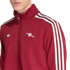 A person wears a maroon Adidas track jacket featuring three white stripes on the sleeves and the Arsenal FC cannon logo on the left chest.