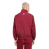 Back view of a man with short blond hair wearing a maroon tracksuit against a black background. The jacket features a small white logo on the upper back.