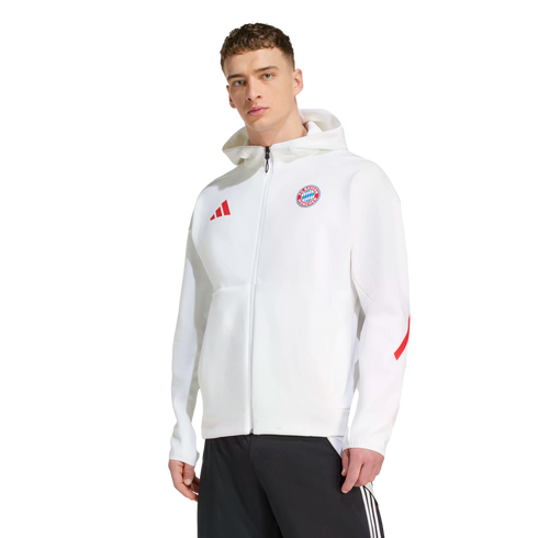 A man wearing a white FC Bayern Munich zip-up hoodie with a red Adidas logo and black track pants.