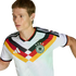 A man wearing a white German football jersey featuring a black, red, and yellow chevron design, looking to his left against a solid black background.