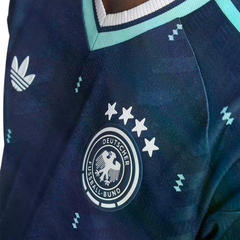 Close-up of a navy blue Adidas Germany soccer jersey featuring the national team crest with four stars and a subtle geometric pattern.