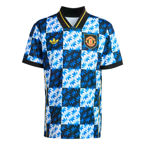 Blue and white checkered Manchester United football jersey with jagged patterns, yellow Adidas logo, and team crest. Features a black v-neck collar and sleeve cuffs.