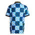 Back view of a jersey with a blue, white, and black checkerboard pattern and jagged geometric shapes. Features a black ribbed collar and cuffs with yellow trim.