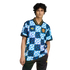 A person wearing a blue and white zig-zag patterned Manchester United soccer jersey and black pants, standing against a black background.