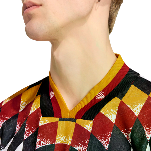 Close-up of a person's neck and jawline wearing a V-neck jersey with a colorful diamond pattern in red, yellow, black, and green. The collar features yellow, red, and black stripes.