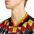 Close-up of a person's neck and jawline wearing a V-neck jersey with a colorful diamond pattern in red, yellow, black, and green. The collar features yellow, red, and black stripes.