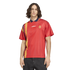 A man wearing a red Adidas Spain soccer jersey with a yellow and blue diamond pattern on the side, paired with dark jeans.