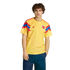 A man modeling a yellow Colombia national football team jersey with red and blue accents on the sleeves, standing against a black background.