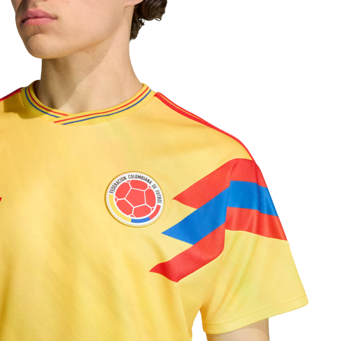 Close-up of a person wearing a yellow Colombia national football team jersey with the team crest and red and blue patterns on the sleeve and collar.
