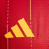 Yellow Adidas logo on a red textured fabric background with vertical yellow dashed lines.