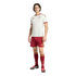 A man models a white and maroon Adidas Spain national football team kit against a black background.