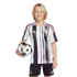 A smiling child with blonde hair wearing a black, white, and pink soccer uniform, holding a matching soccer ball under one arm against a white background.