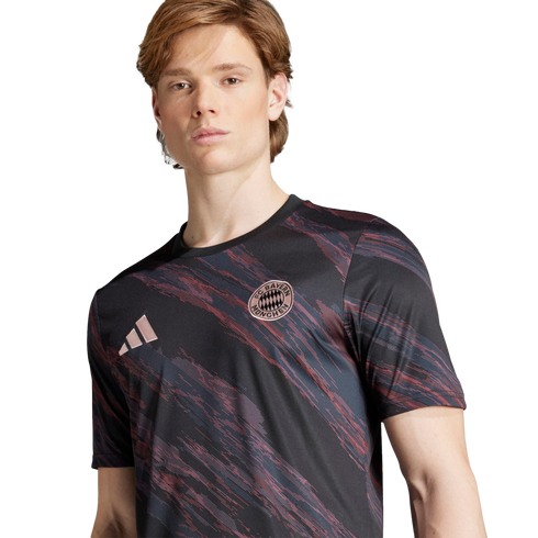 A man wearing a black FC Bayern Munich jersey with pink diagonal brushstroke patterns and the Adidas logo.
