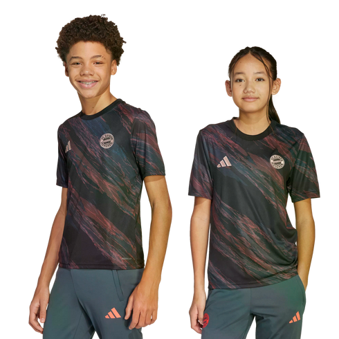 A boy and a girl pose in matching black FC Bayern Munich soccer jerseys with a pink and green swirled pattern, standing against a white background.