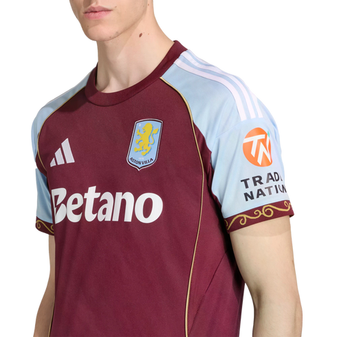 Close-up of a person wearing an Aston Villa home football jersey, featuring a maroon body, light blue sleeves, and the Betano sponsor logo.