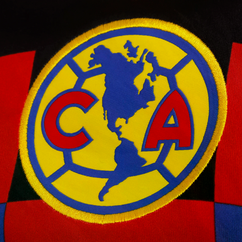 Embroidered Club América soccer crest on a checkered jersey, featuring a yellow circle with a blue map of the Americas flanked by red letters "C" and "A."