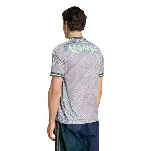 Back view of a man in a gray patterned jersey with "Corona" in mint green lettering and dark blue shorts, set against a black background.