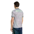 Back view of a man in a gray patterned jersey with "Corona" in mint green lettering and dark blue shorts, set against a black background.