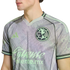 Close-up of a man wearing a grey and pale green Adidas Club América soccer jersey with the team crest and Caliente sponsor logo.