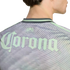 A close-up of the back of a person wearing a light green and grey patterned sports jersey with an Estadio Azteca emblem and a large Corona logo.