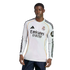 A young Black man models a white long-sleeved Real Madrid soccer jersey with black Adidas stripes and sponsor logos.