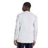 Rear view of a man wearing a white long-sleeved athletic shirt with black sleeve stripes and dark blue shorts.