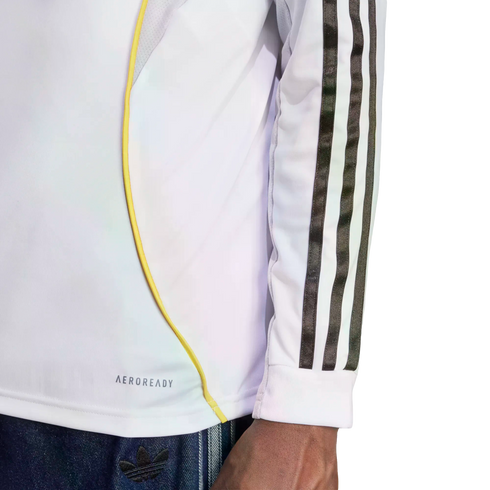Side view of a white long-sleeve athletic shirt featuring black stripes on the sleeve, a yellow curved accent line, and "AEROREADY" text near the bottom hem.