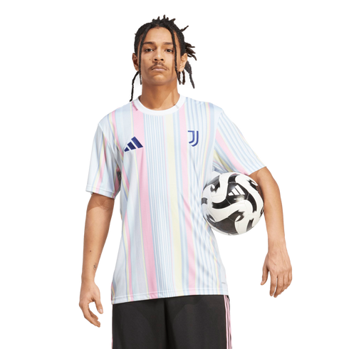A man with dreadlocks wears a pastel-striped Juventus soccer jersey and black shorts, holding a soccer ball against a white background.
