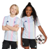Two children smile in matching blue, pink, and yellow striped Juventus soccer kits. The girl holds a soccer ball against a white background.
