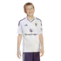 A smiling boy wearing a white and purple Manchester United soccer jersey with a Snapdragon logo, standing against a black background.