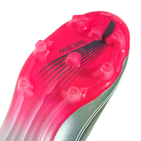Close-up of a vibrant pink and silver soccer cleat sole with clear studs and "MESSI" branding.