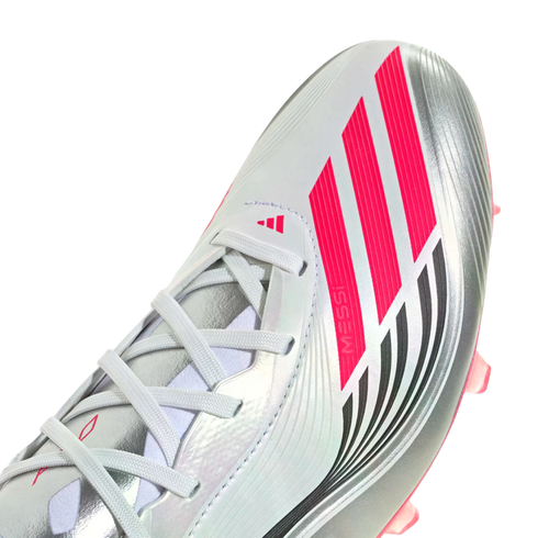 Close-up of a silver Adidas soccer cleat featuring vibrant pink stripes, "MESSI" branding, and white laces.