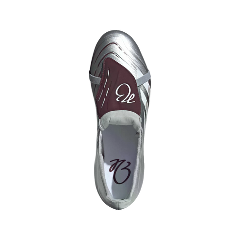 Top-down view of a silver metallic soccer cleat with a maroon fold-over tongue featuring a white script logo.