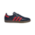 Profile view of a navy blue Adidas Samba sneaker with three red stripes and a gum sole.