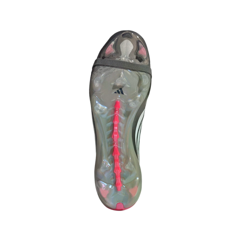Bottom view of an Adidas soccer cleat soleplate, featuring a translucent gray base with pink studs and a central pink spine. A gray strap crosses the forefoot.