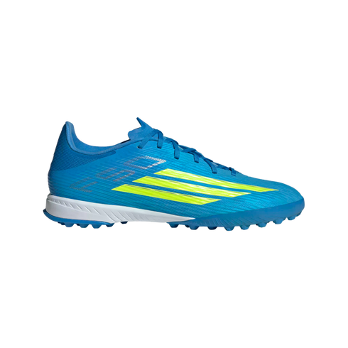 A side profile of a vibrant blue Adidas soccer turf shoe with three neon yellow stripes on a solid black background.