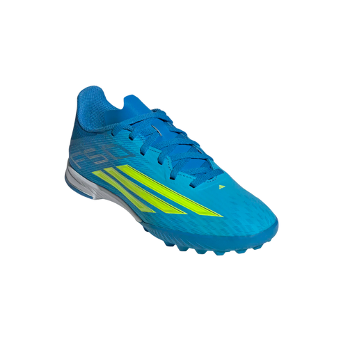 A bright blue Adidas soccer shoe with lime green accents, angled from the front/side against a solid black background. The shoe features blue laces and a multi-studded rubber outsole designed for artificial turf.
