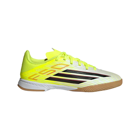 A side profile of a bright yellow and white Adidas indoor soccer shoe with black stripes and a gum rubber sole, set against a black background.